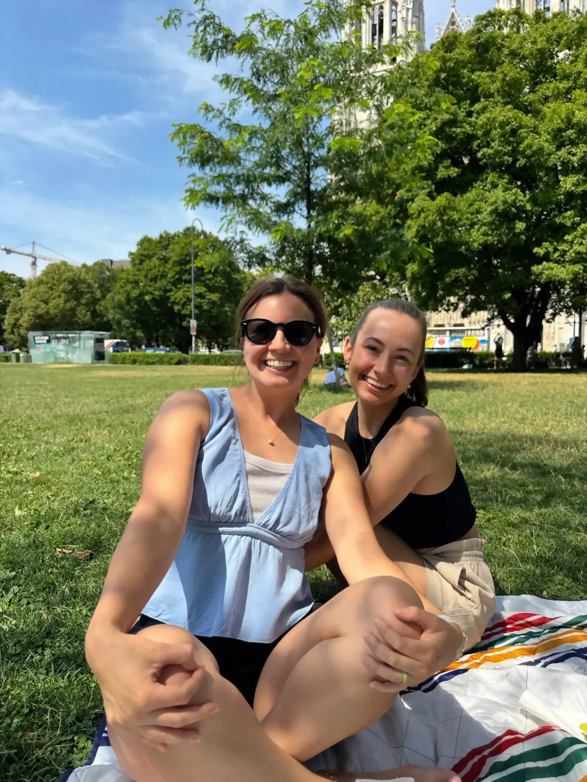 Two students laughing on a picnic blanket in a Vienna park