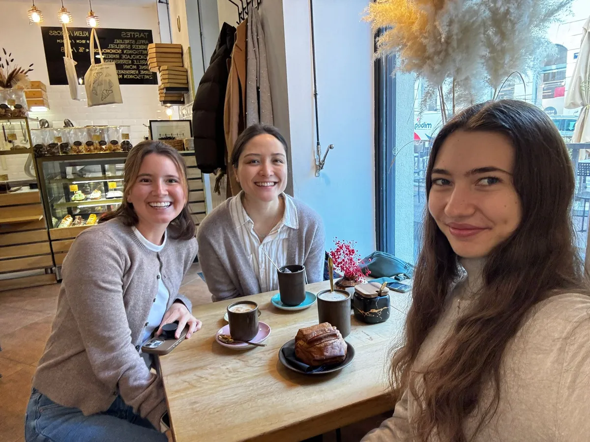 Three students talking over coffee and cake in a café