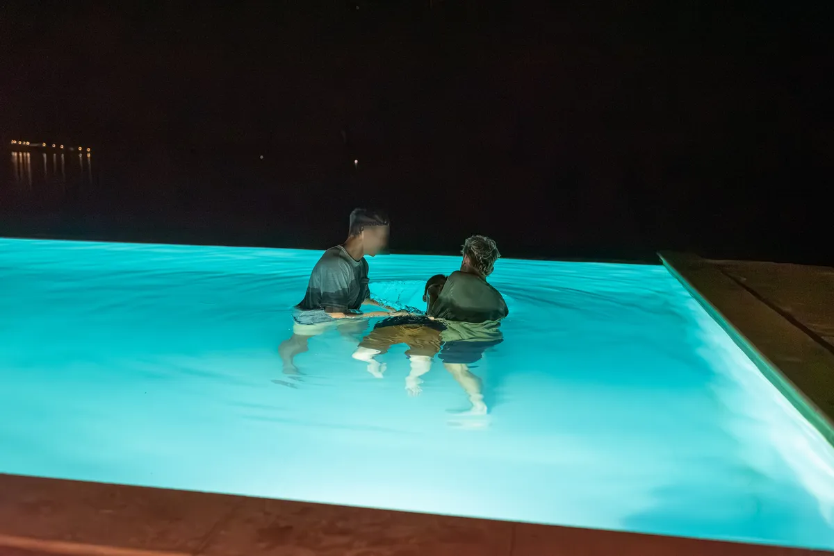 A baptism in a lit pool at night