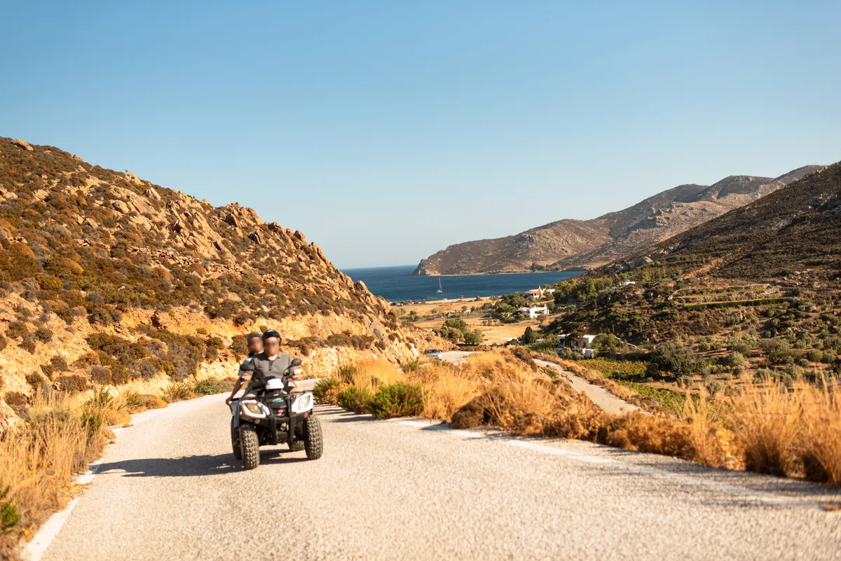 Two students on a quad bike on a coastal road