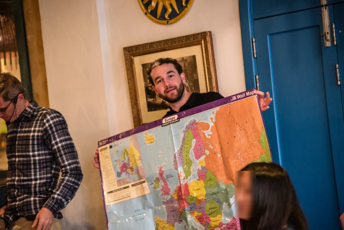 A student holding up a wall map of Europe during an evening session