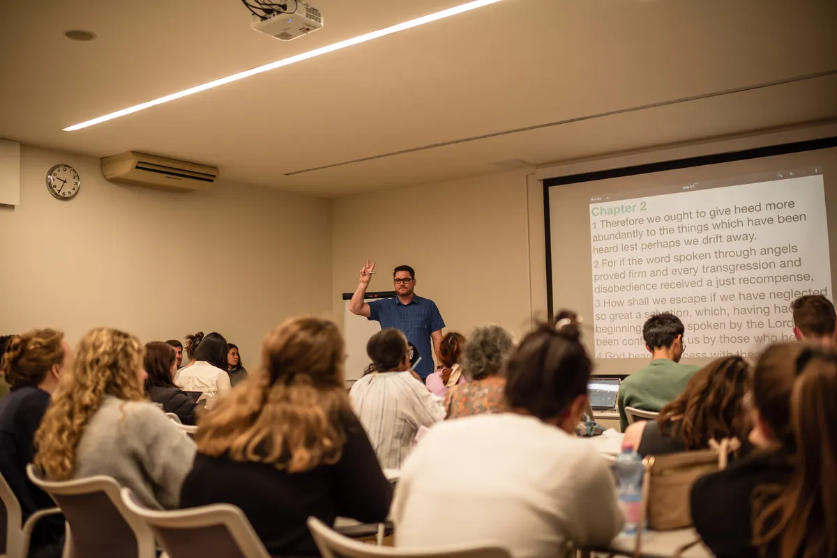 A teaching session in a lecture room, the text on the screen behind