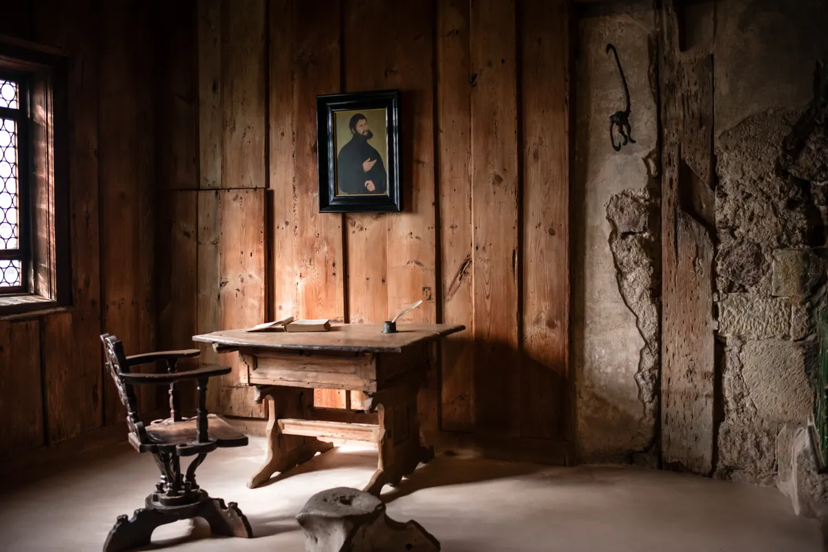 A wood-panelled study with a writing desk beneath a portrait of Luther