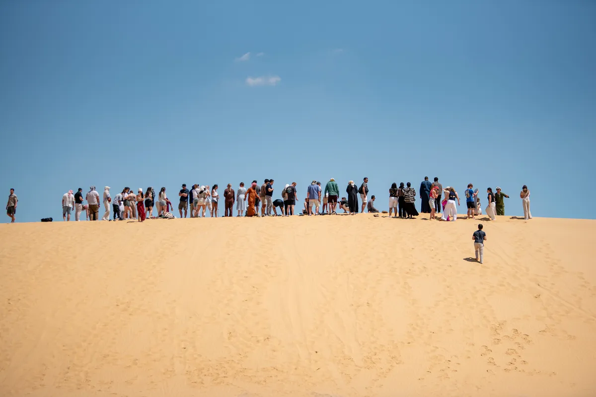 Students walking the crest of a desert dune