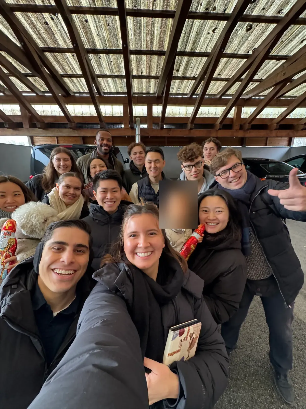 Students packed together for a selfie under fairy lights at a Christmas market